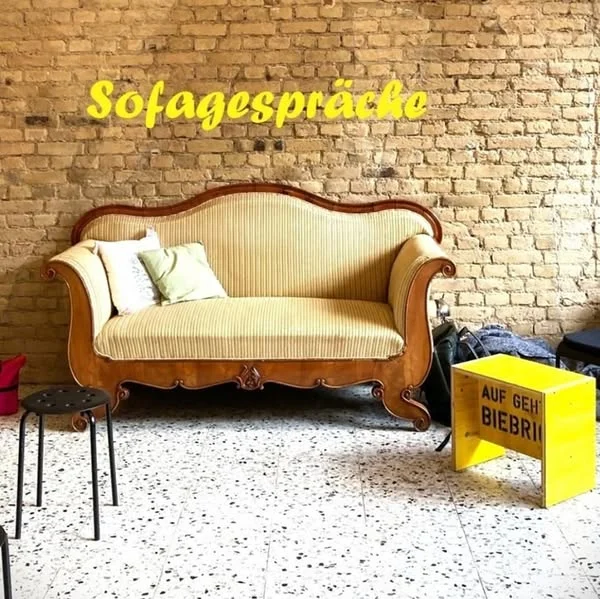 Sofagespräche: gelbes Sofa vor einer Backsteinwand